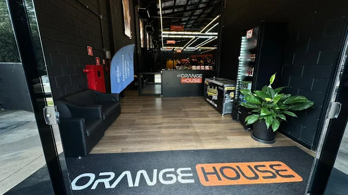 Recepção do CT Orange House com balcão preto e logo iluminado