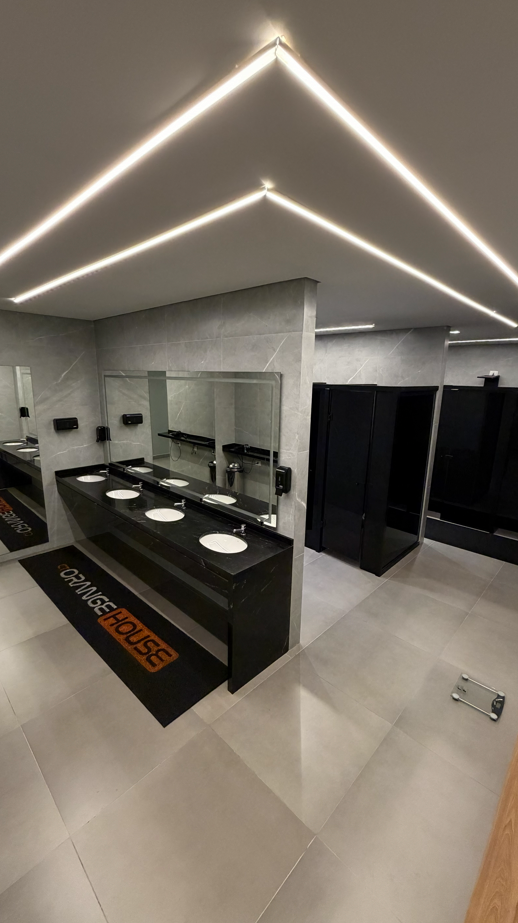 Vestiário premium do CT Orange House com bancada preta e espelhos